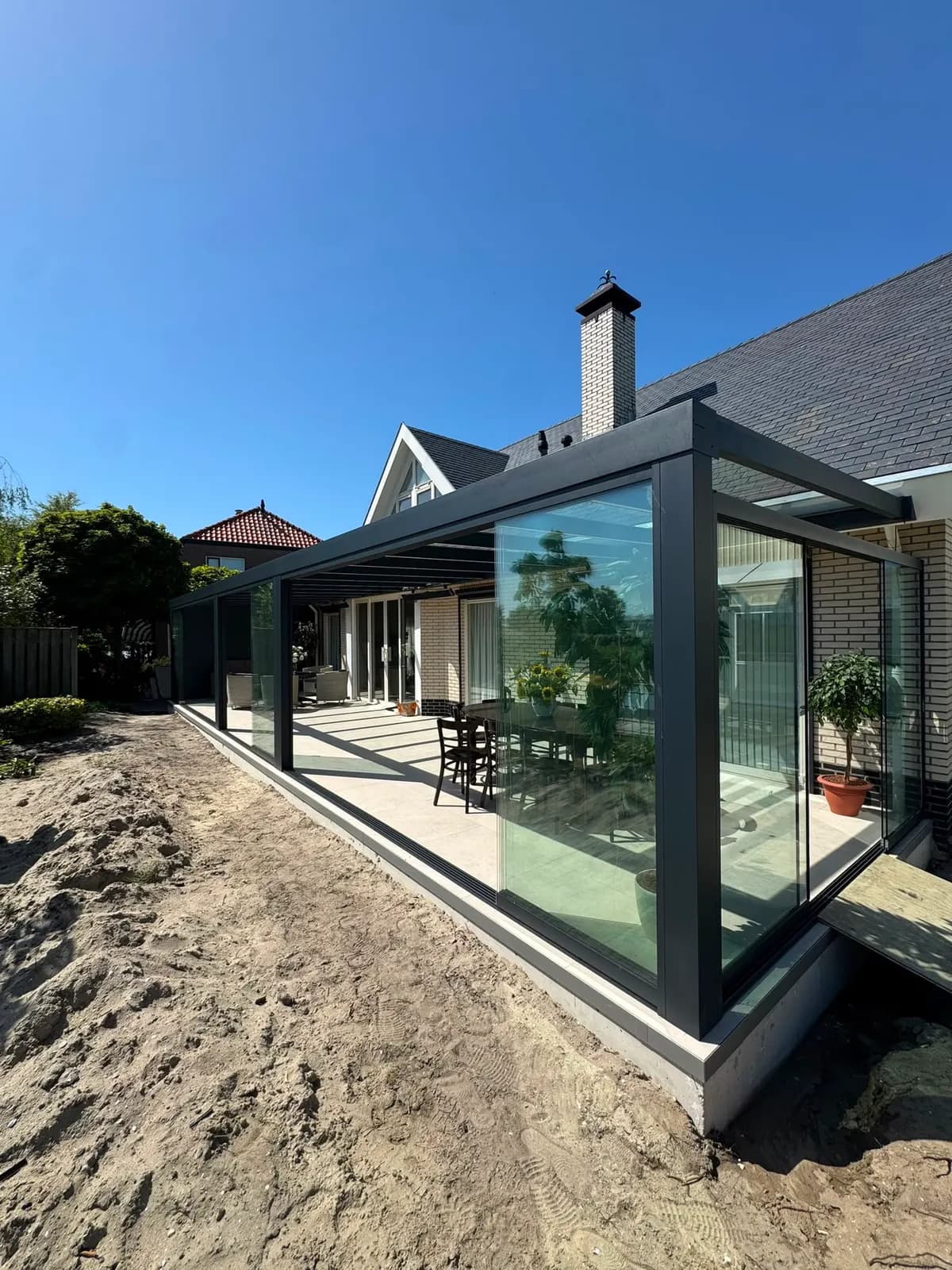 Glazen aanbouw met antraciet schuifwanden bij een vrijstaande woning