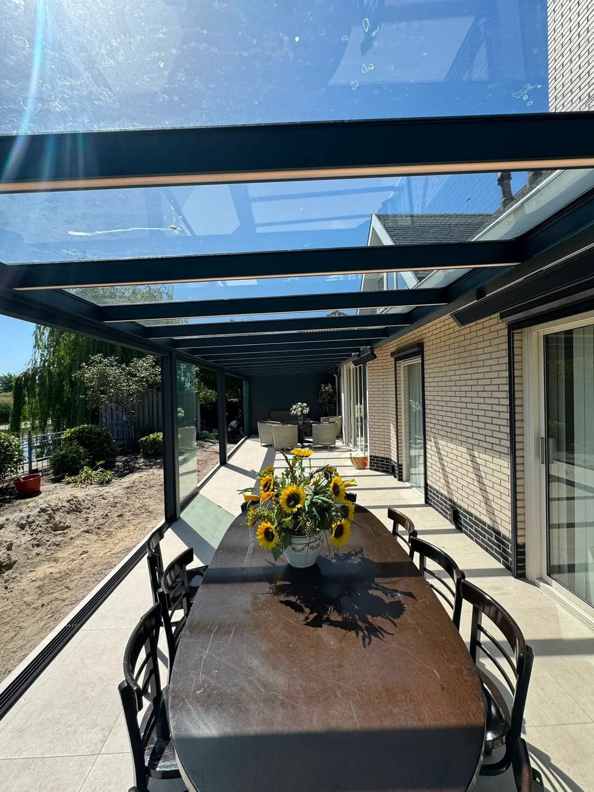 Veranda met glazen dak en gedekte tafel in de tuin